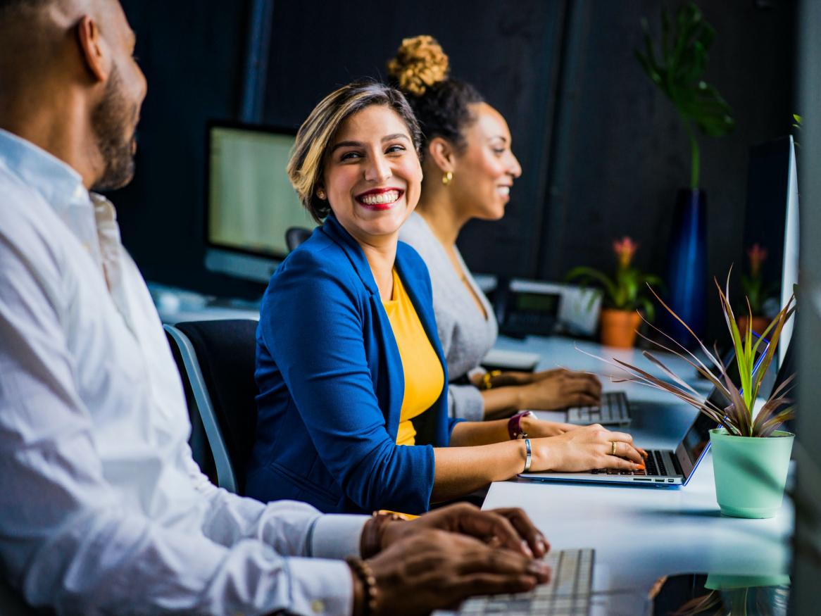Woman smiling at desk towards co-worker