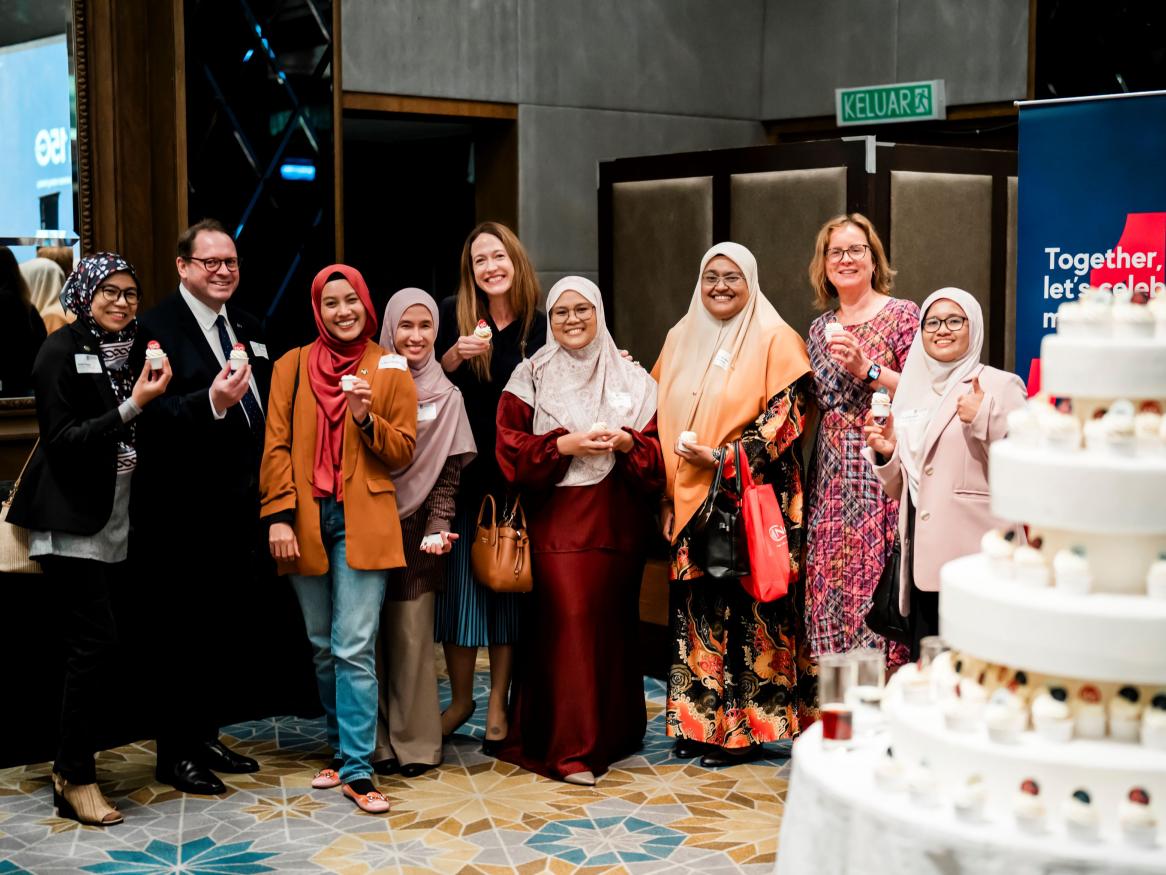 A group of 8 alumni with DVCEE in Malaysia, holding cupcakes